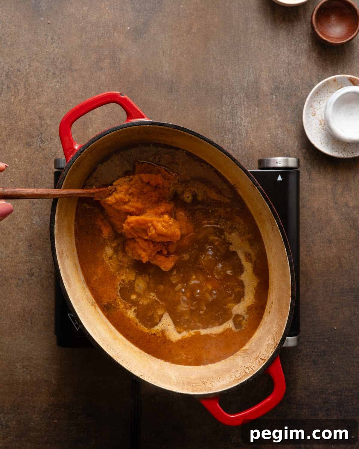 canned pumpkin being added into soup pot.