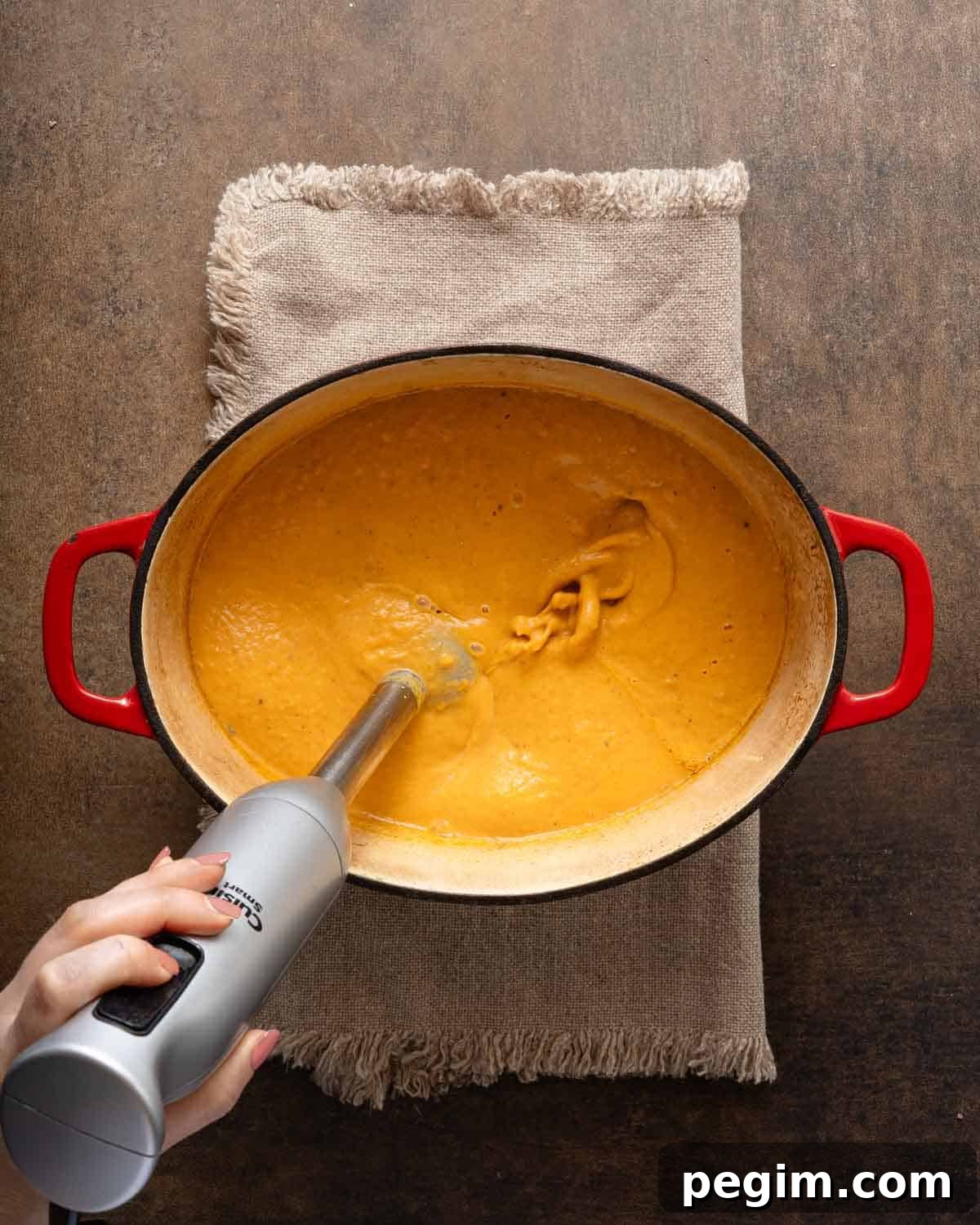 sweet potato pumpkin soup being blended with stick blender.