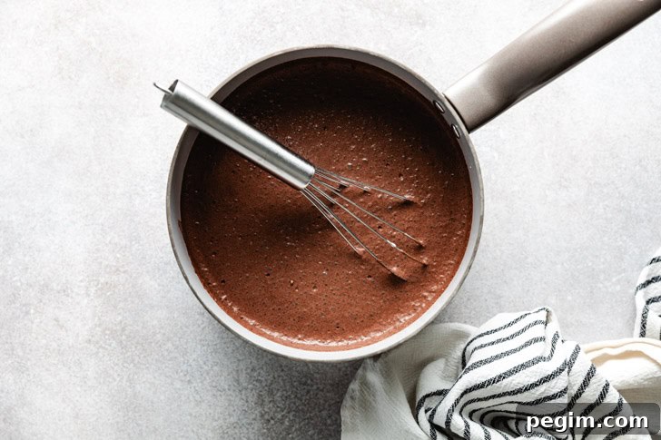 A saucepan with a whisk resting inside, filled with freshly made chocolate mixture.