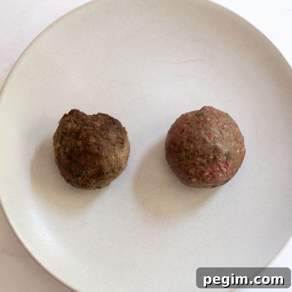 a baked and a fried meatball on a plate.