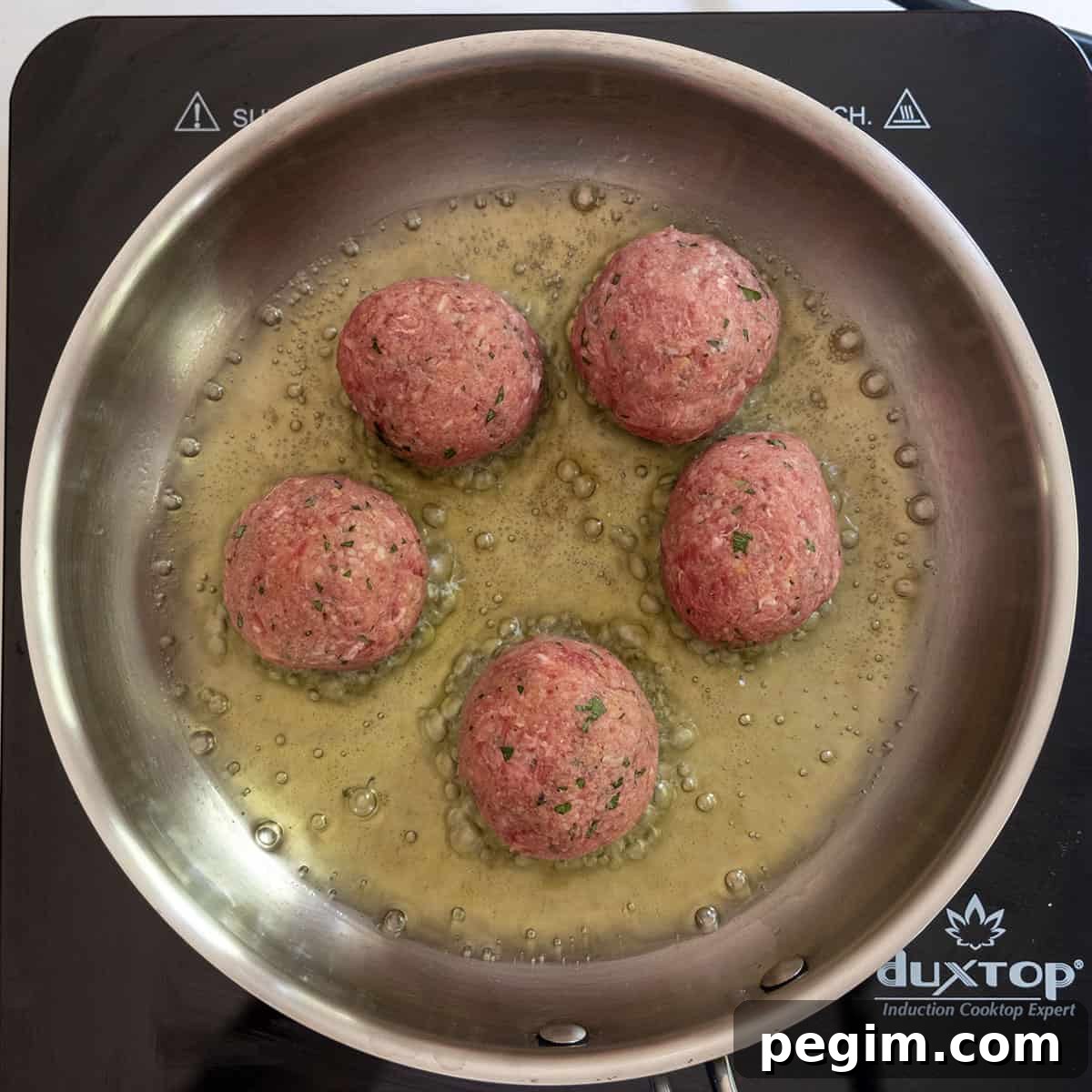meatballs frying in frying pan.