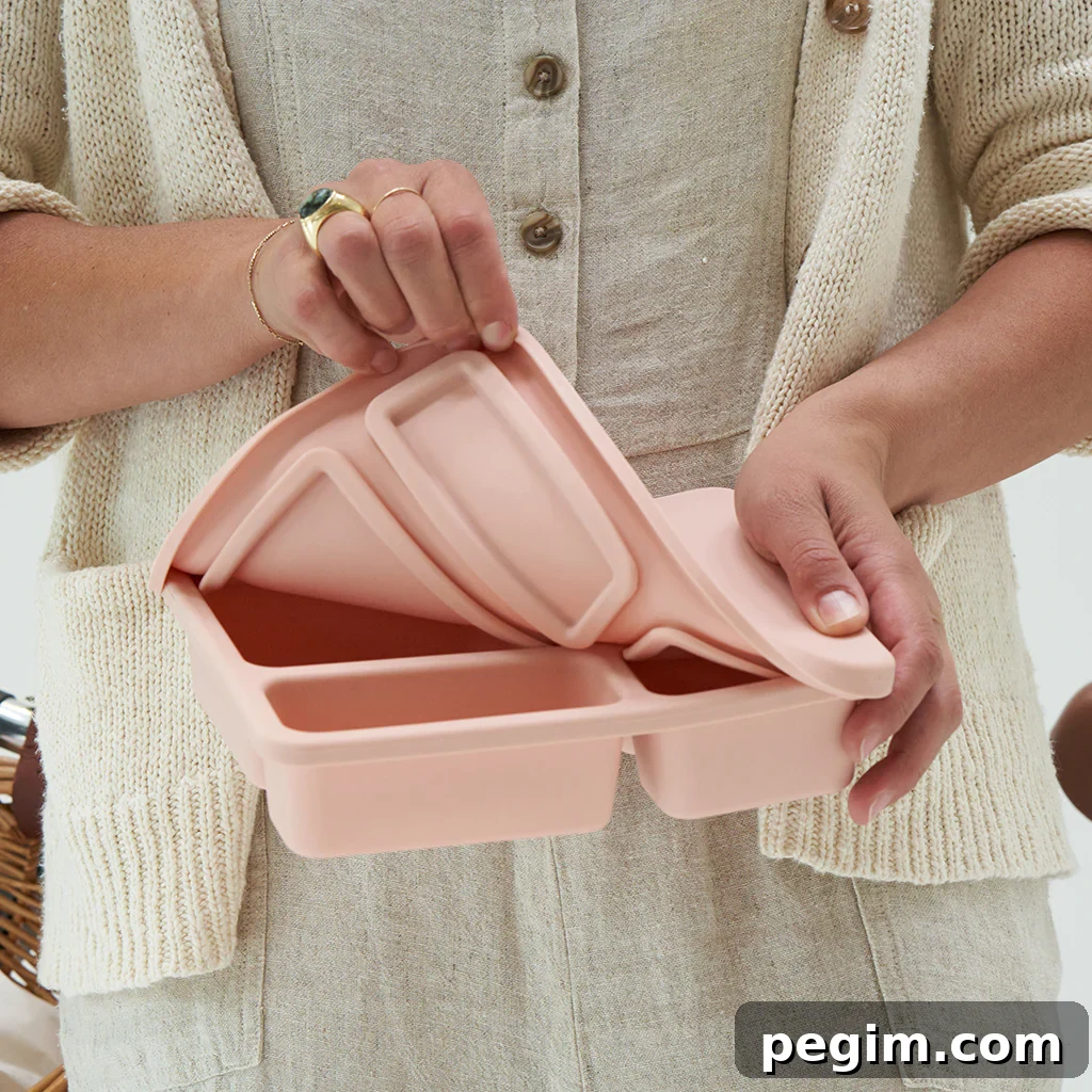 A woman showcasing a blush pink silicone bento box from the Austin Baby Collection, designed to be leak-proof.