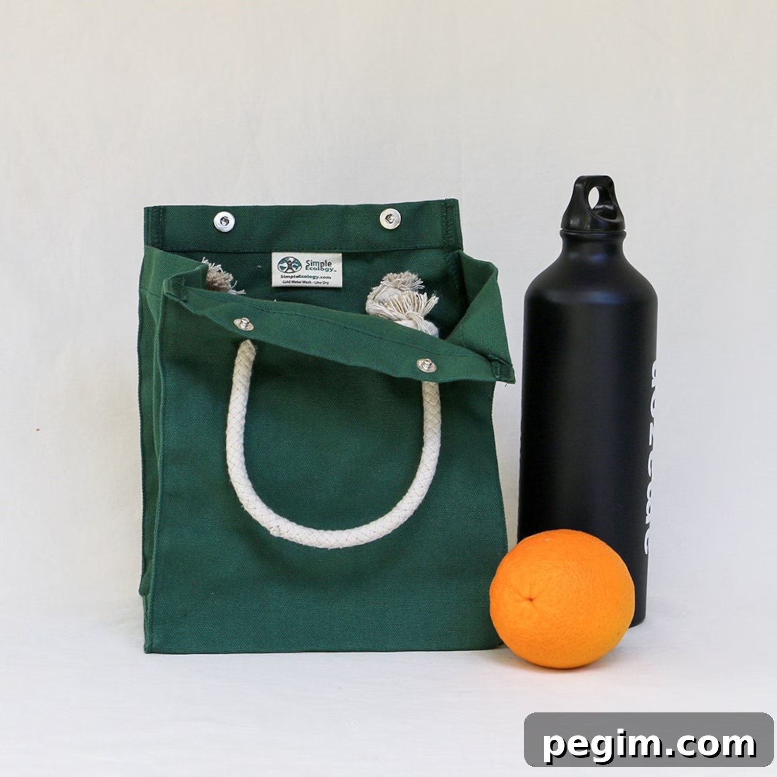 A shot of an Etsy eco-friendly lunch bag, accompanied by a stainless steel tumbler and a fresh orange.
