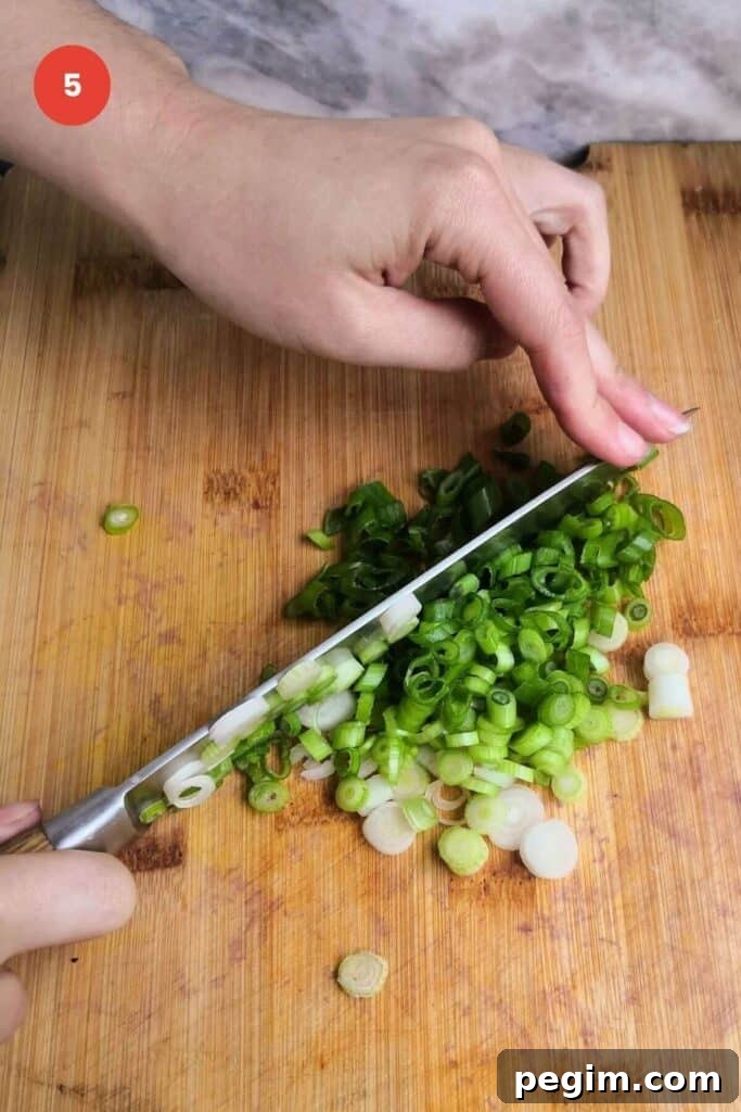 Slicing scallions with a knife on a cutting board.