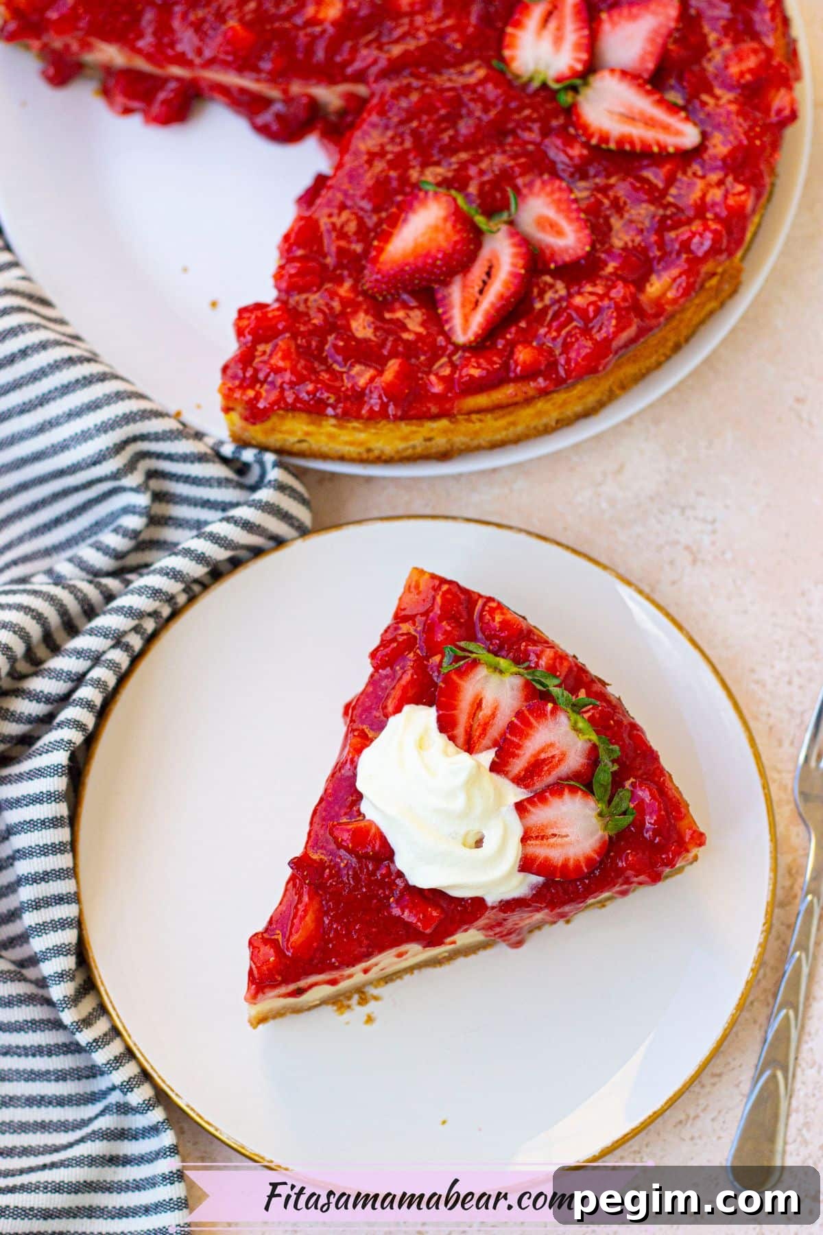 Protein cheesecake topped with strawberries topping on a white plate with more cheesecake behind it.