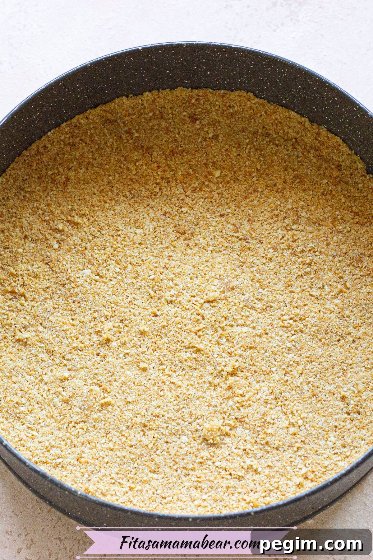 Graham cracker crust pressed into a circular baking pan.