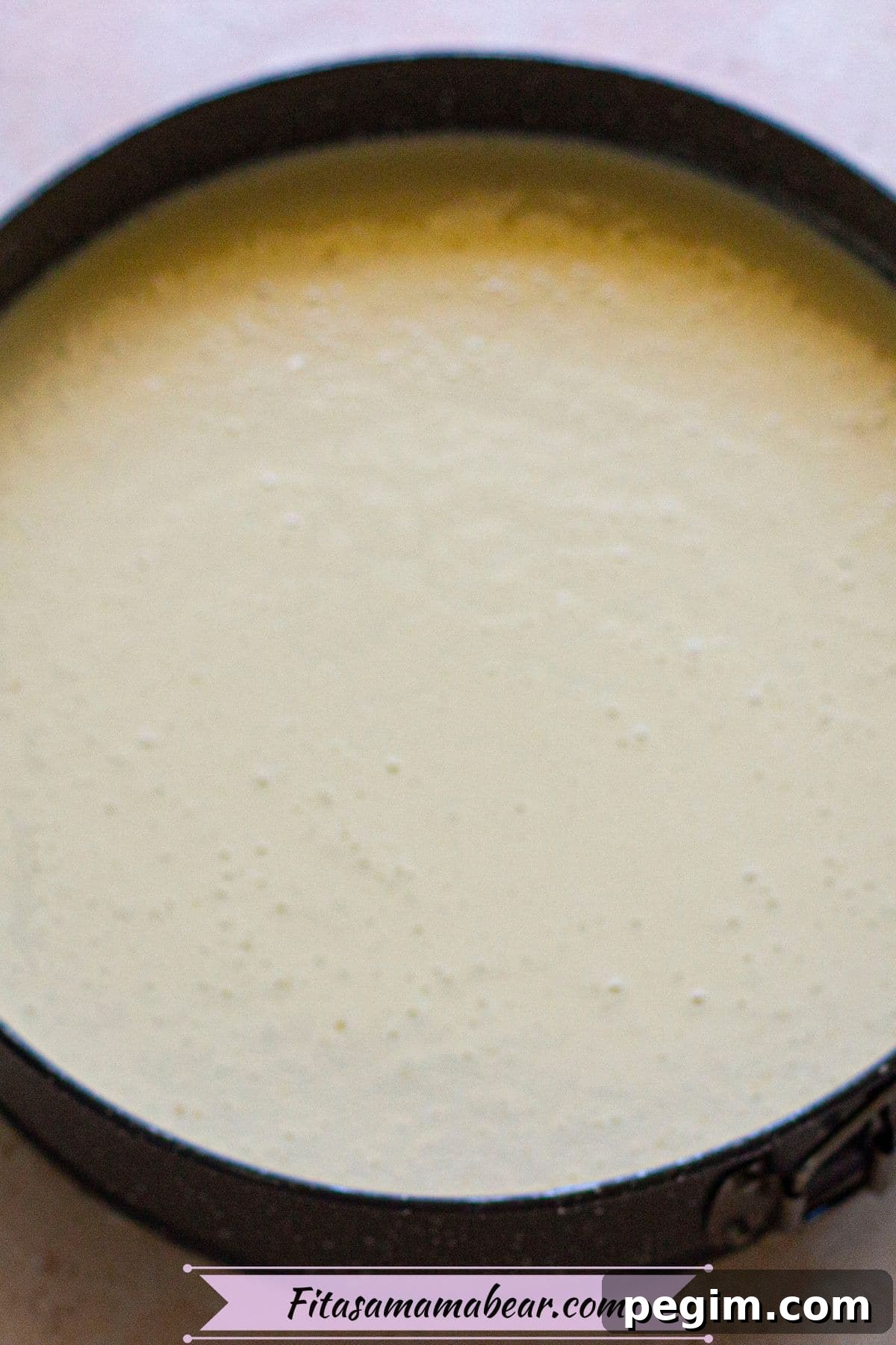 Raw cheesecake batter in a circular baking pan.