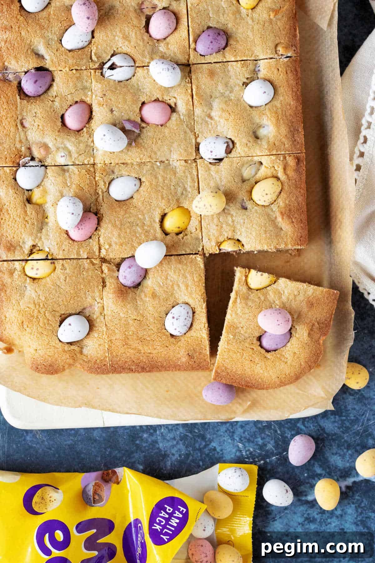 Chocolate mini egg cookie bars cut into squares on a wooden board.