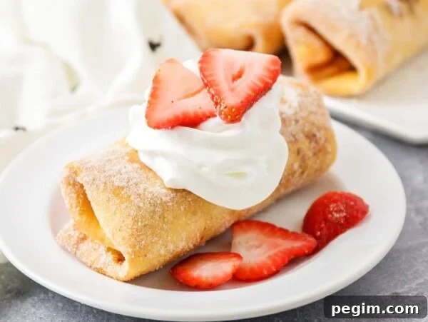 A cheesecake chimichanga served with whipped cream and fresh sliced strawberries.