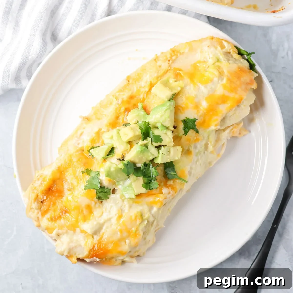 Two creamy chicken enchiladas on a white plate.