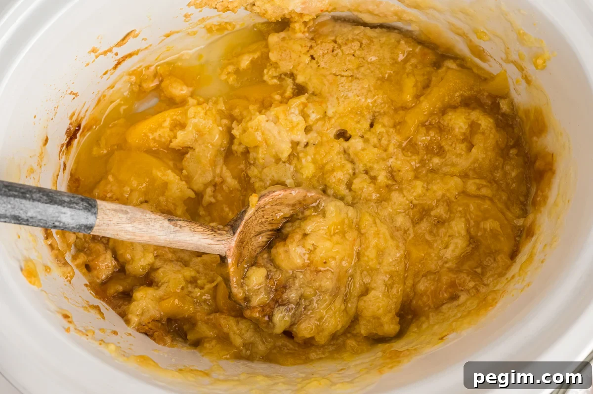 crockpot with peach cobbler with some dished out.