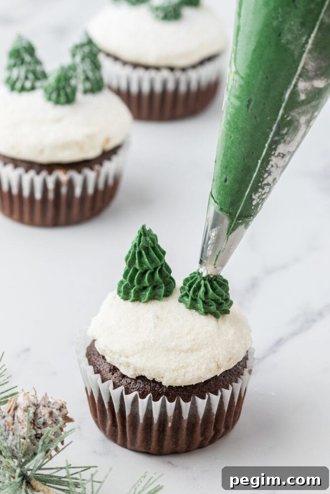 picture of a hand piping a tree out of green buttercream frosting on a mint chocolate cupcake
