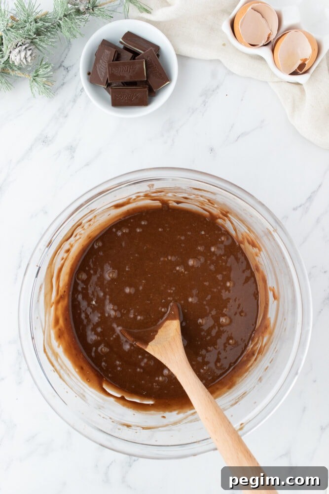 chocolate mint cupcake batter being mixed in a bowl with a wooden spoon on a table