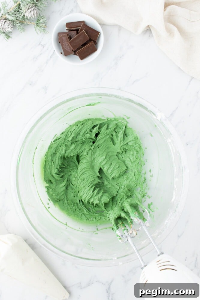 mixed green buttercream frosting in a glass bowl on a marble table
