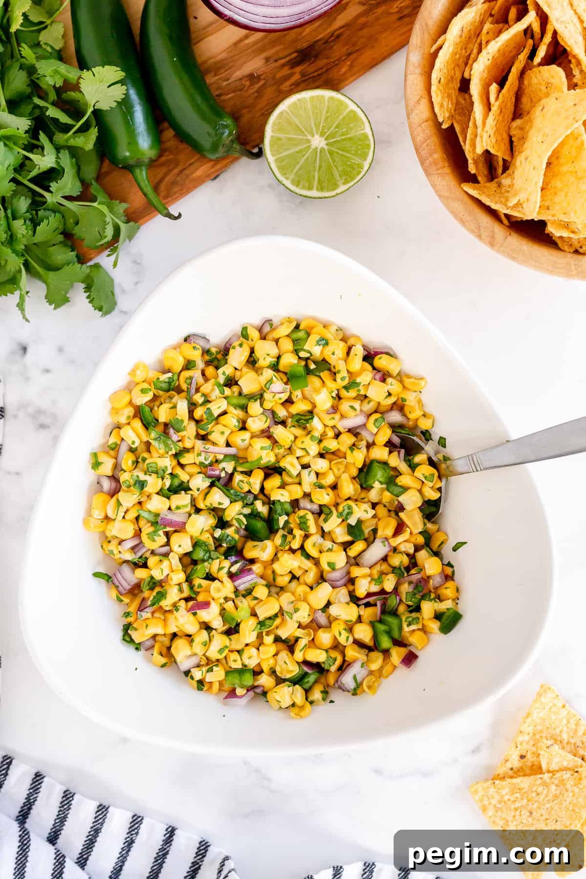Corn Salsa in a white serving bowl with a spoon.