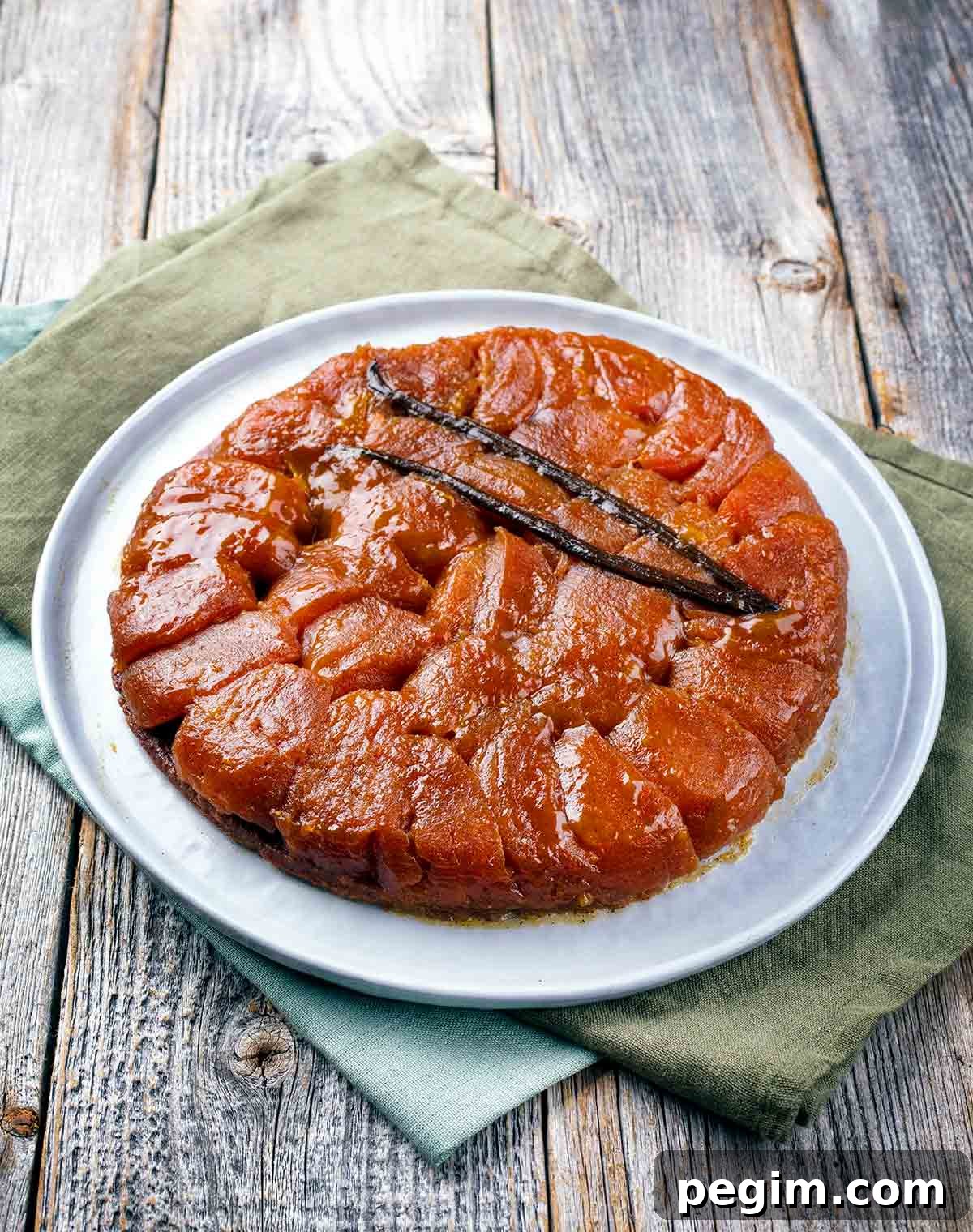 A tarte tatin on a white plate on a wooden table.