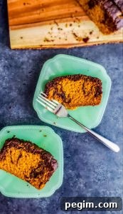 Two pieces of pumpkin spice loaf cake on teal plates on a gray counter top.