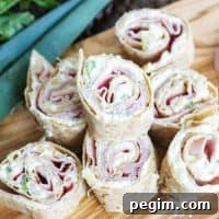Ham & Pineapple Hawaiian Tortilla Roll Ups stacked up on a cutting board