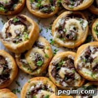 Philly Cheese Steak Pinwheels piled up on a baking sheet