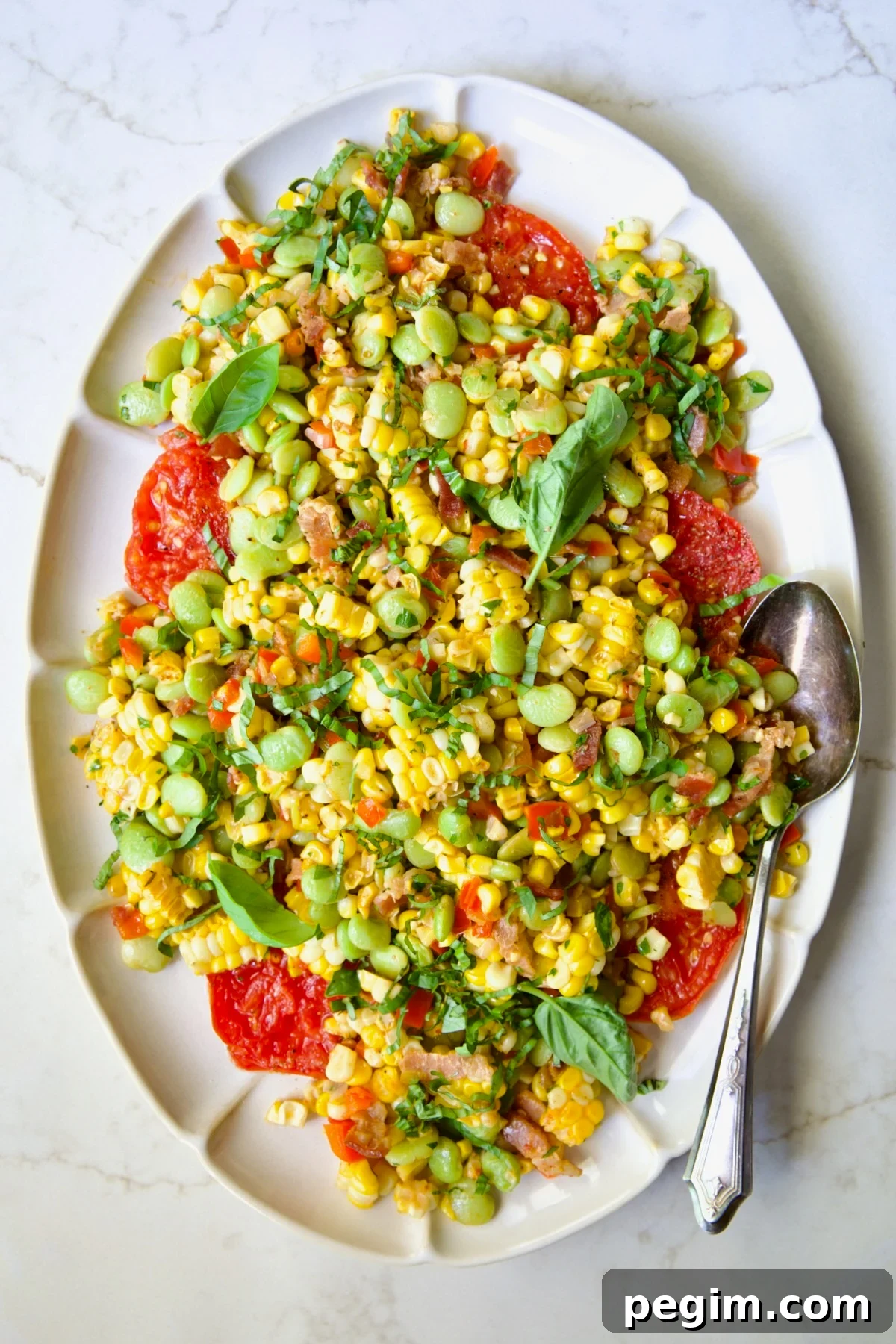 Grilled Corn Succotash on white oval platter garnished with fresh basil leaves.
