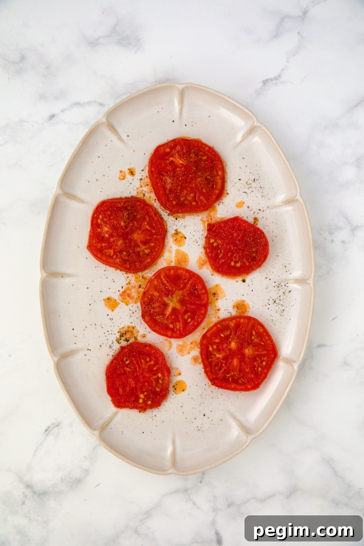 Six grilled tomato slices on white oval platter.