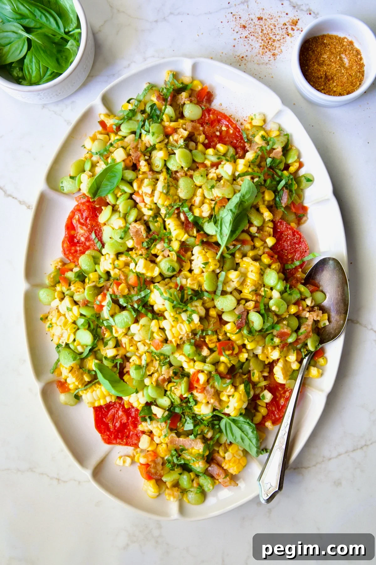 Grilled Corn Succotash on white oval platter garnished with fresh basil leaves.