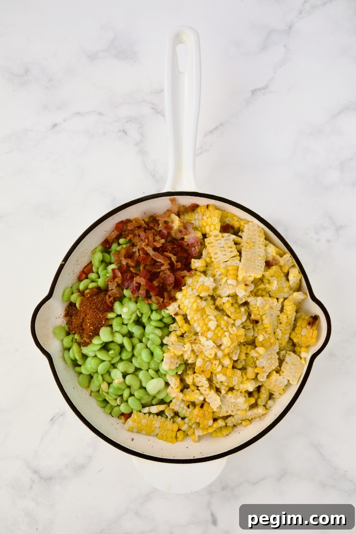 Corn, lima beans and bacon added to red bell pepper and scallion in white enamel cast iron skillet.