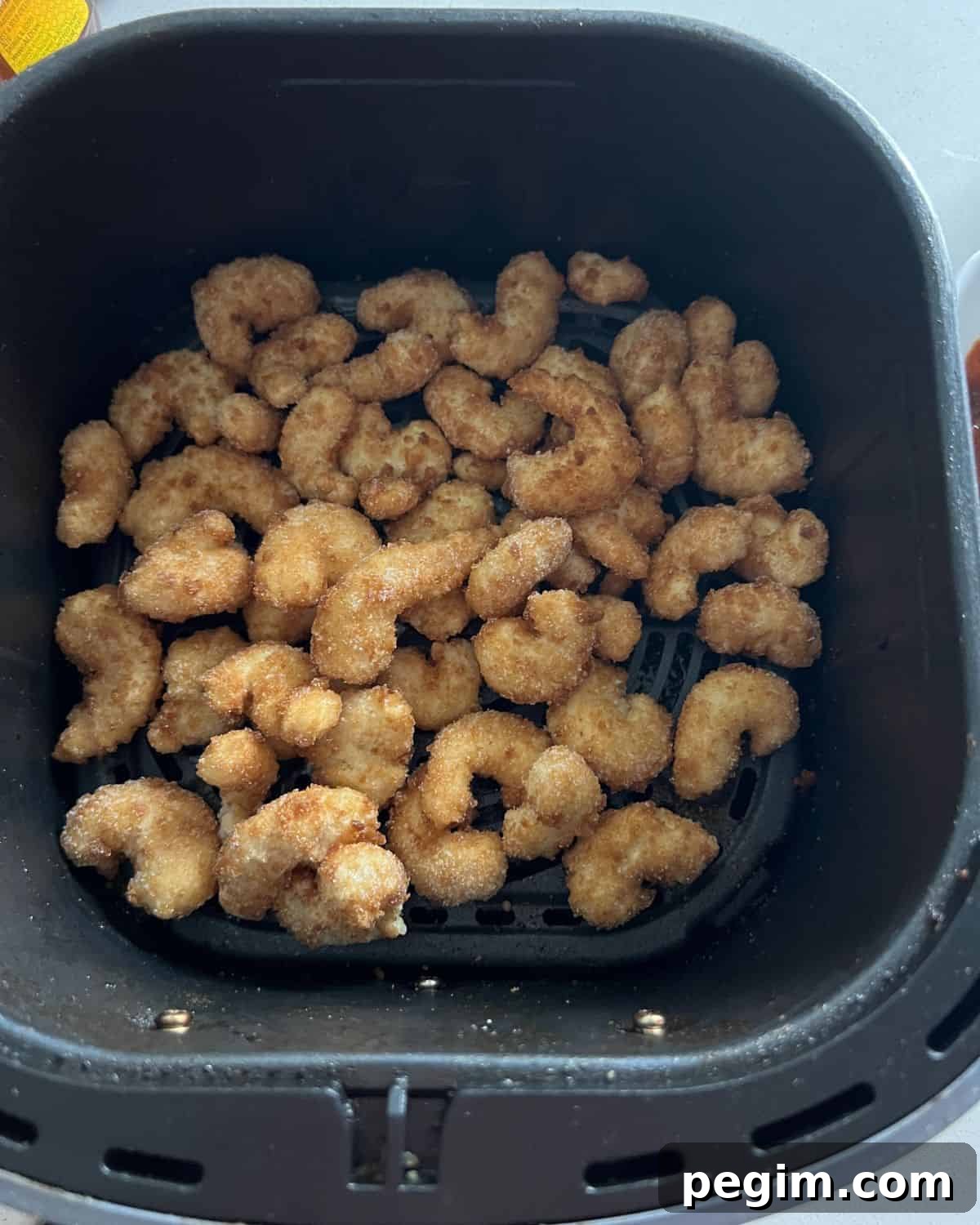 Popcorn shrimp in air fryer basket.