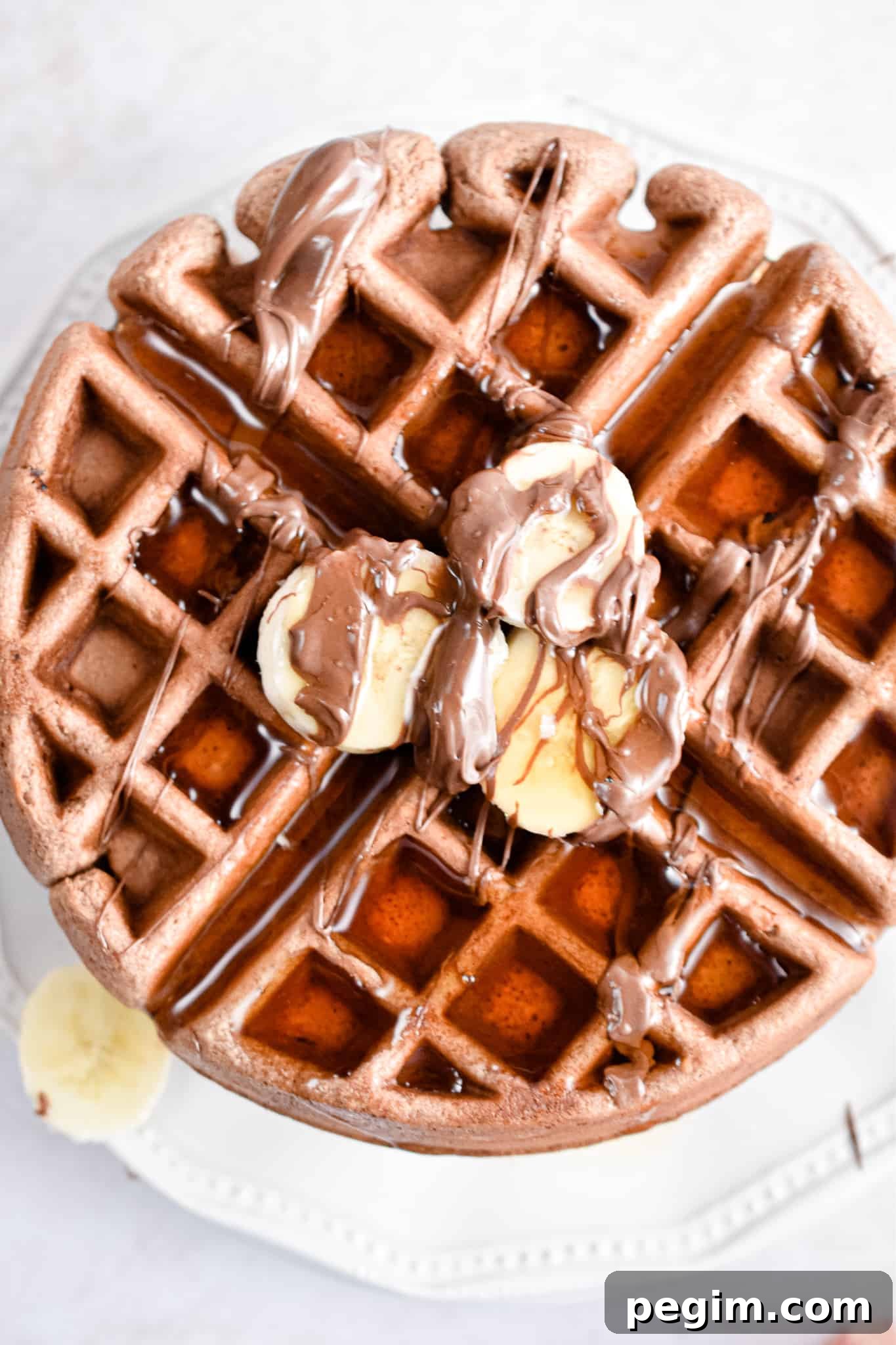 An overhead shot of the Nutella waffles with maple syrup and bananas.