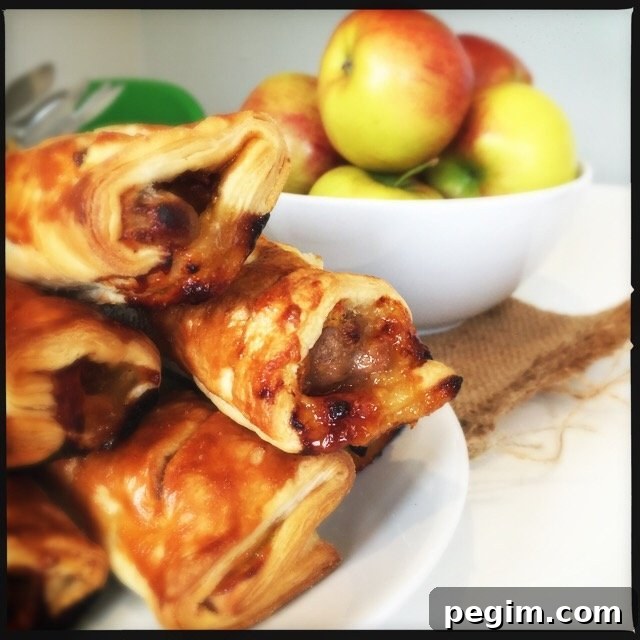plate piled high with homemade sausage rolls with chutney and cheese - bowl of apples in the background