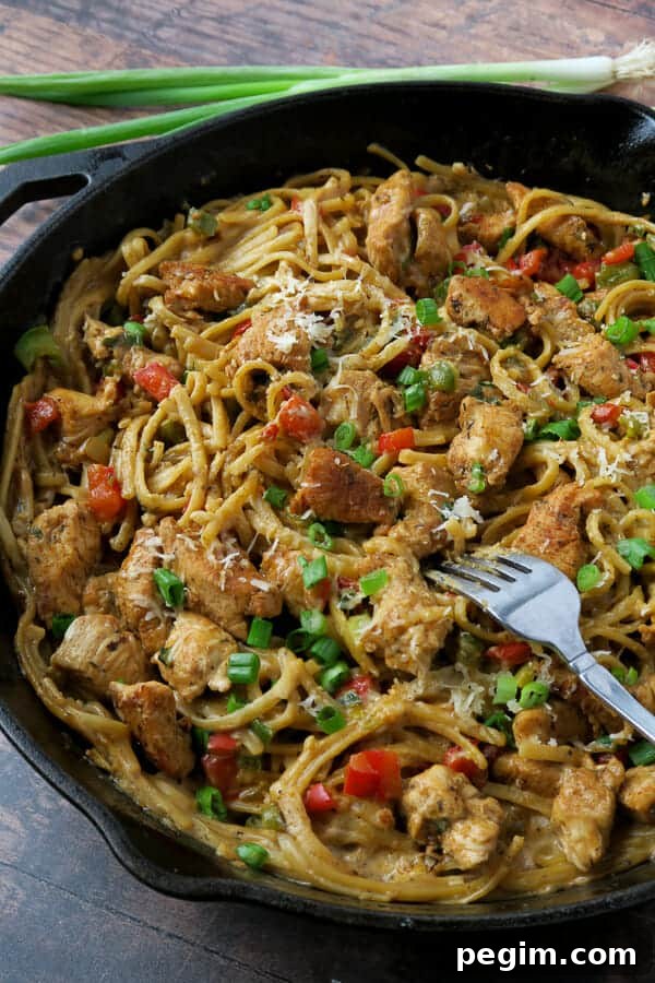 one pot creamy cajun chicken pasta topped with green onions and grated parmesan cheese