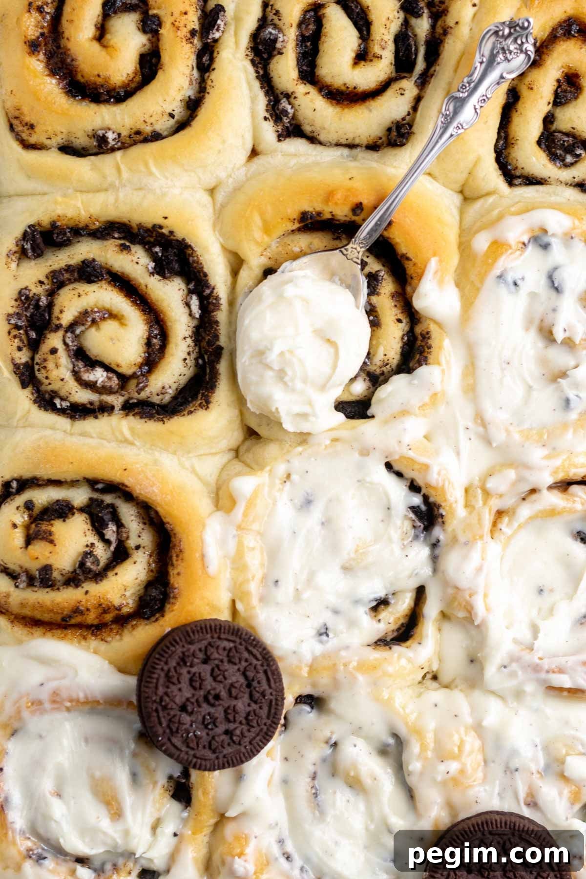 spoon with vanilla icing on top of baked oreo cinnamon rolls