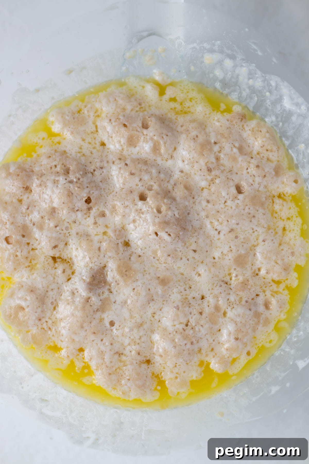 activated yeast with sugar, milk and melted butter in a mixing bowl