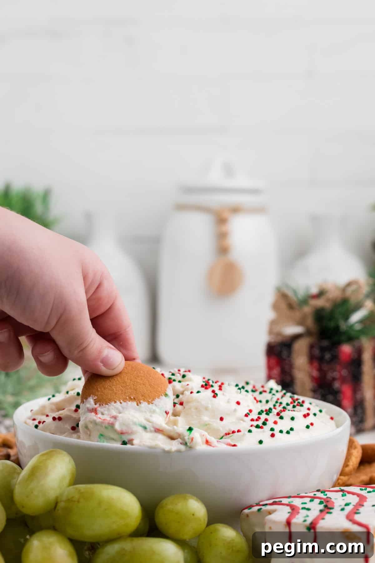 A child's hand dipping a cookie into Christmas Tree Dip.