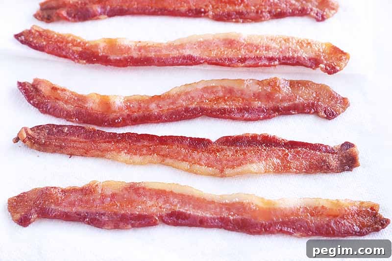 Horizontal image of draining strips of cooked meat on paper towels.