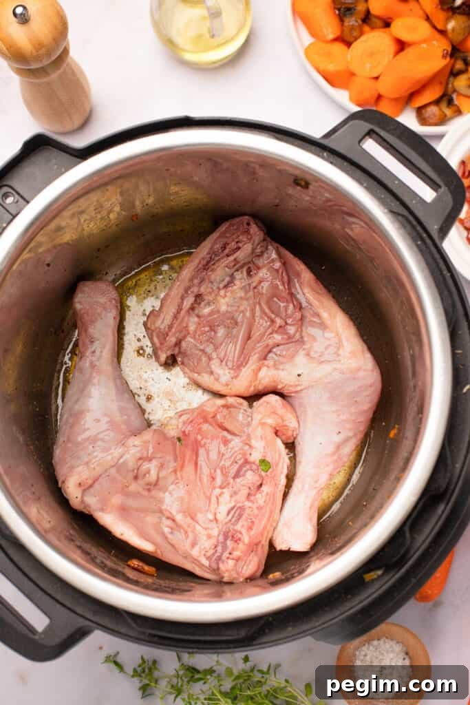 Marinated chicken legs frying in the bottom of an Instant Pot.