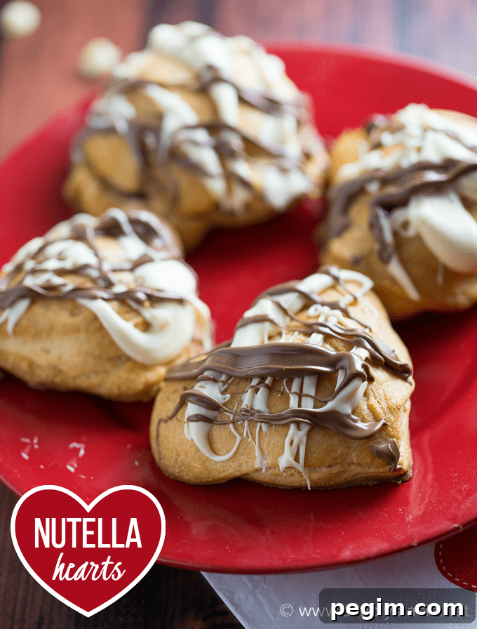 Heart-Shaped Nutella Cookies Recipe for Valentine's Day 4 Nutella Hearts - Smooth, creamy Nutella nestled inside a buttery heart-shaped croissant with drizzled milk and white chocolate on top. This Valentine's Day dessert is sublime!