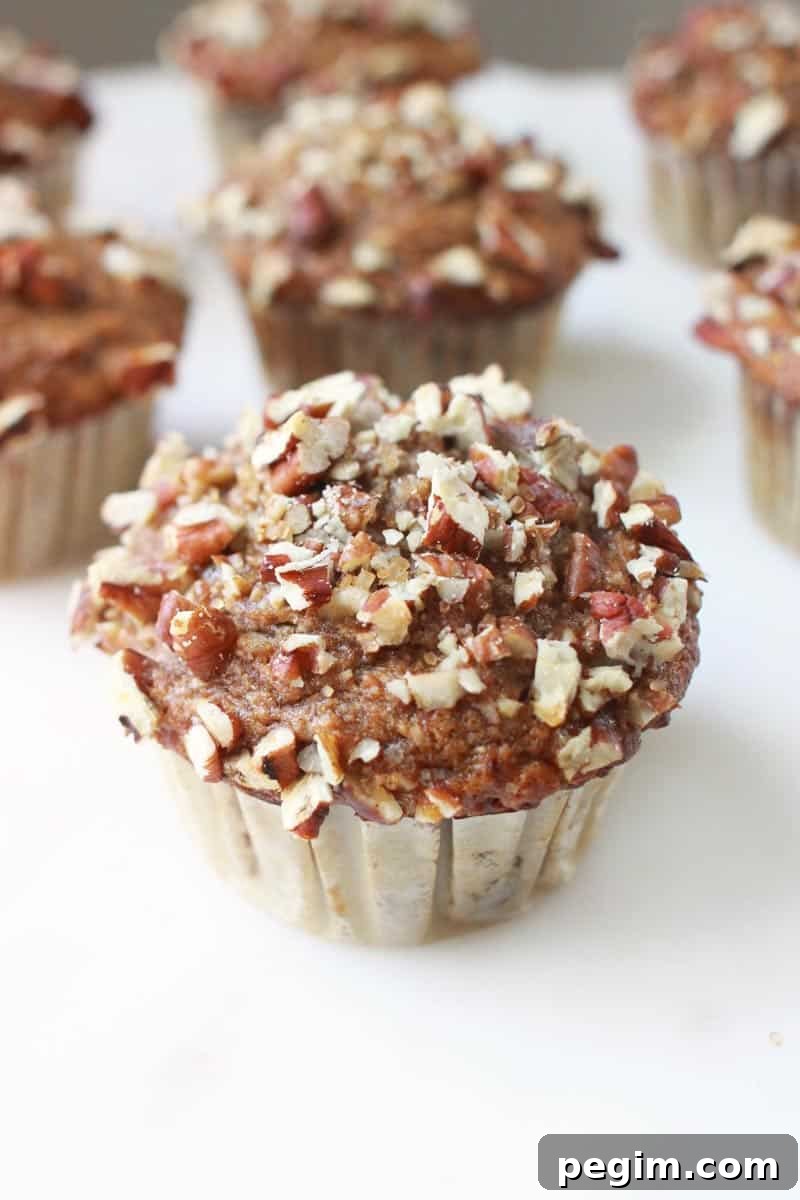 Whole Wheat Banana Nut Muffins Recipe 2 banana nut muffins on a white marble cutting board