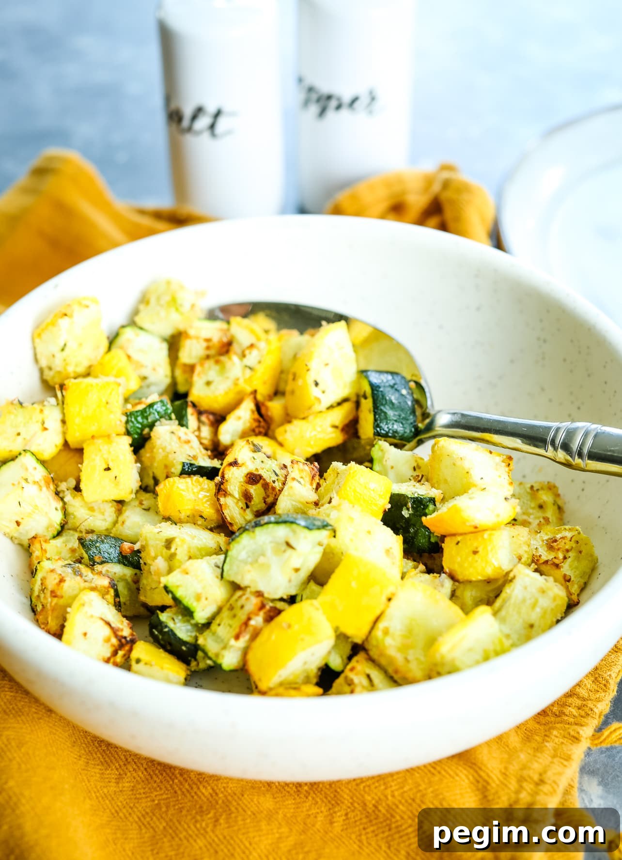 Crispy Air Fryer Zucchini and Yellow Squash in 15 Minutes 8 scooping out zucchini and squash from a white bowl