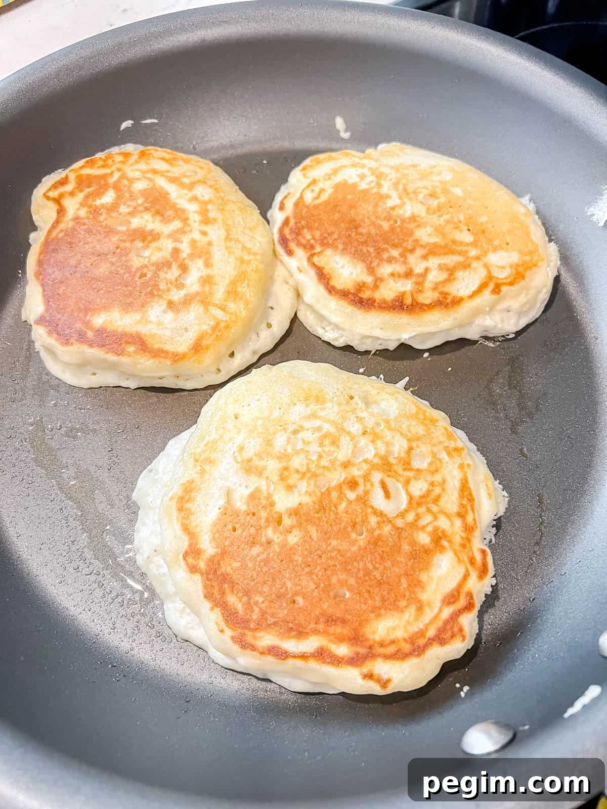 Fluffy Greek Yogurt Pancakes That Stay Light and Tender 8 Greek yogurt pancakes after flipping on a pan.