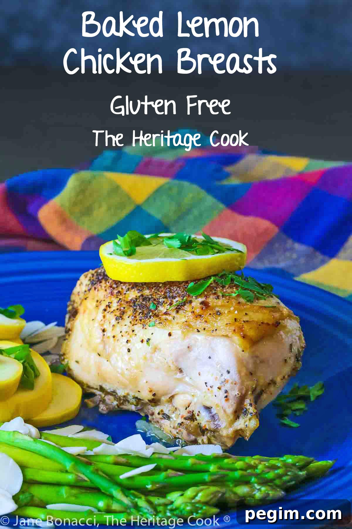 Large baked lemon chicken breast with a slice of lemon on top and green asparagus next to yellow squash on a blue plate © 2024 Jane Bonacci, The Heritage Cook. 