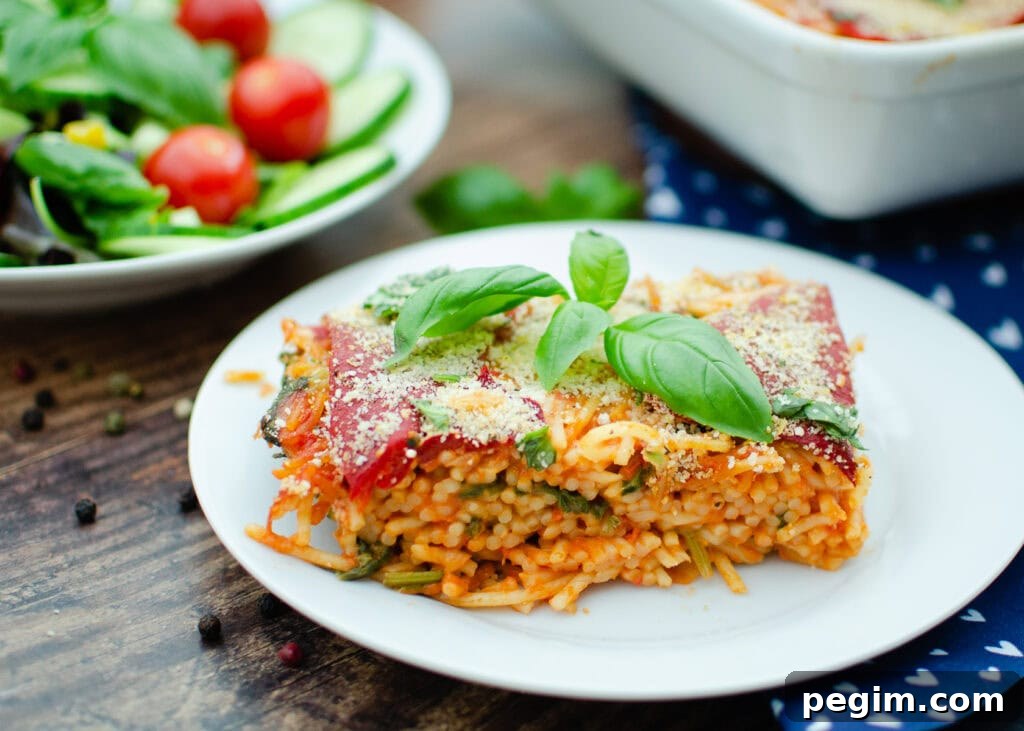 Sun-Dried Tomato & Roasted Pepper Pasta Recipe for Quick Weeknights 7 Sundried Tomato and Roasted Pepper Pasta served on a white plate with a side salad in the background