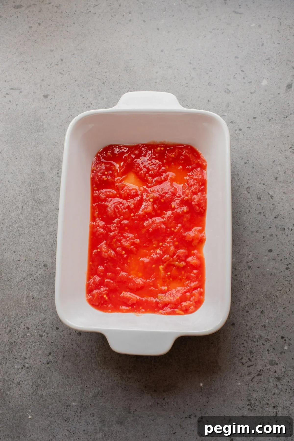 Crispy Baked Eggplant Parmesan Recipe 7 An overhead image of spreading a layer of marinara sauce on a baking sheet.