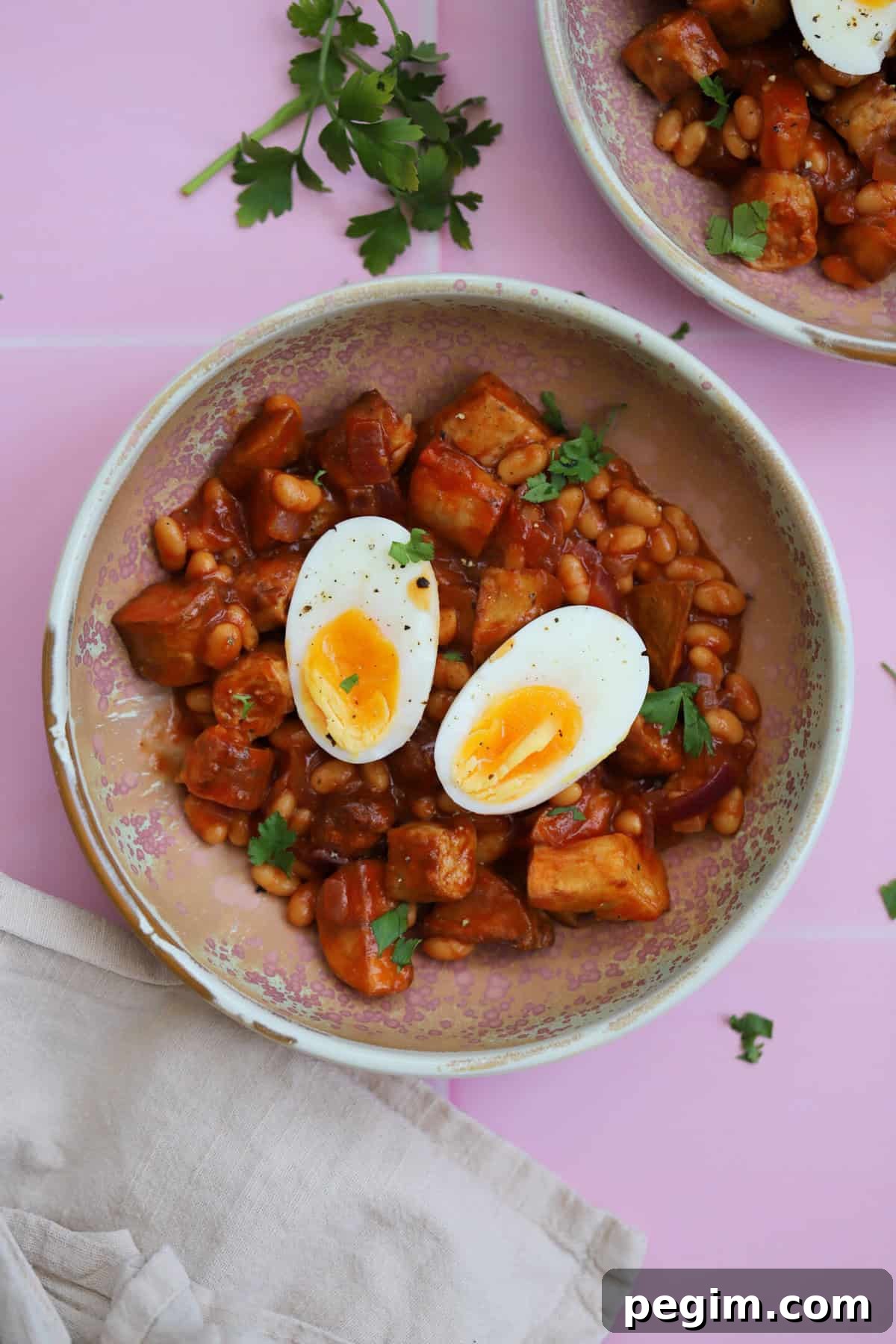 Hearty One-Pan Breakfast Bowl with Eggs and Veggies 2 A bowl of chicken sausage pieces, beans and potatoes with a boiled egg on top.