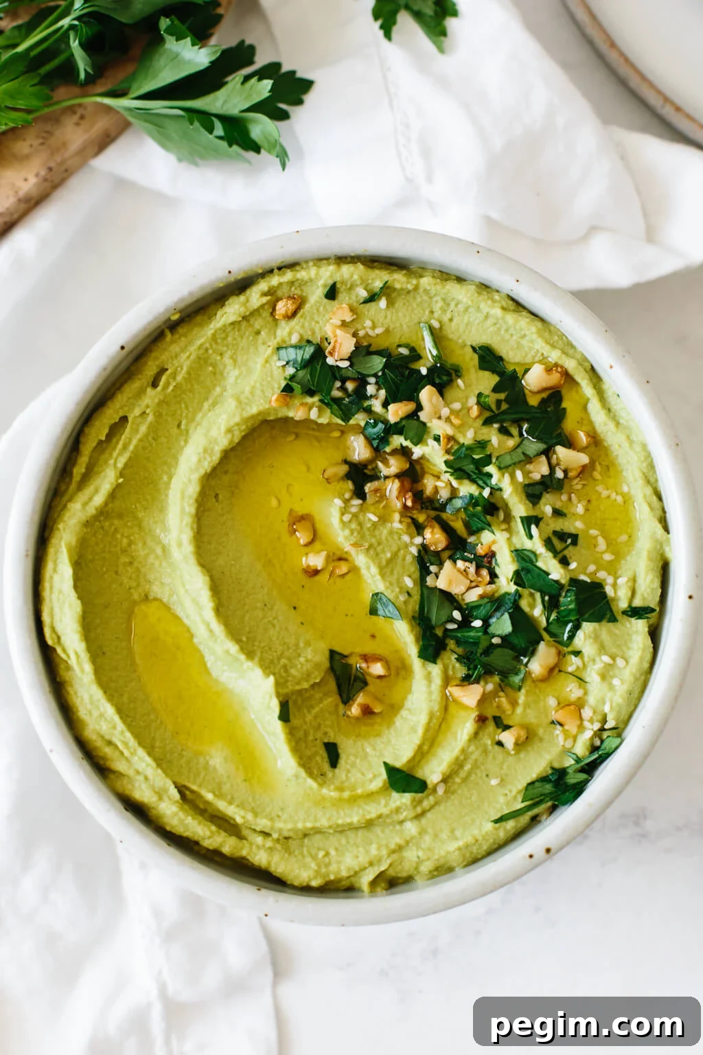 45+ Delicious Vitamix Recipes for Every Meal 2 Green hummus in a bowl with herbs and toppings.
