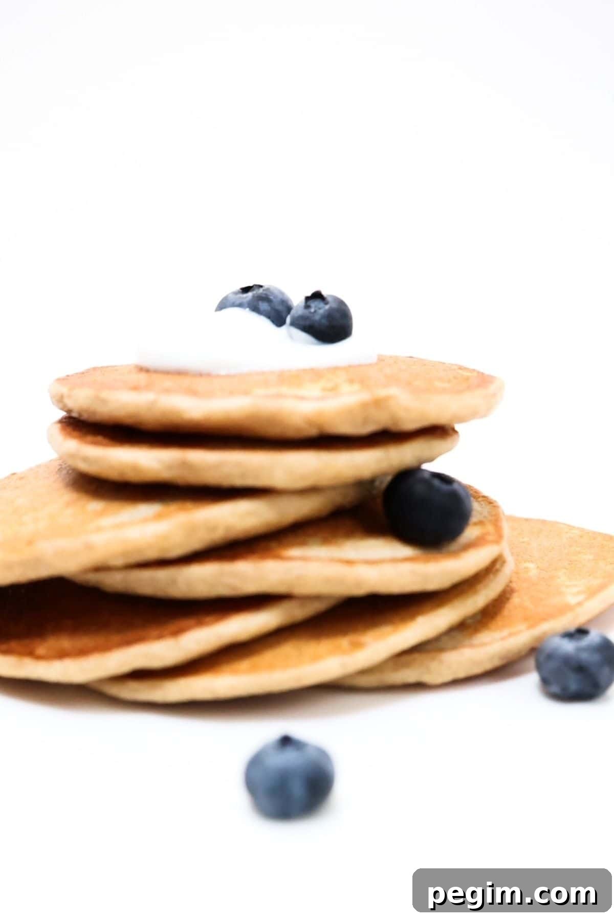 Protein-Packed Pancakes Without Protein Powder: High-Protein Recipe 2 A stack of protein pancakes topped with a small amount of yogurt and blueberries.