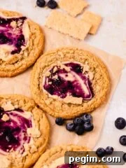 blueberry cheesecake cookies on parchment paper with fresh blueberries around
