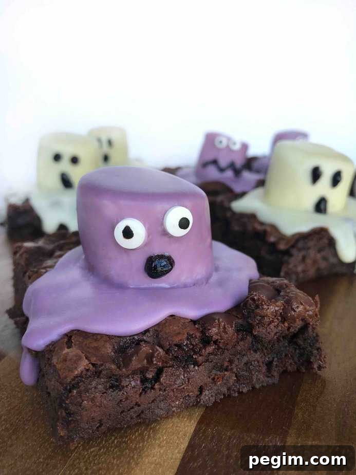 Monster Bash Brownies Recipe and Halloween Traditions 3 purple monster brownie with OH shaped mouth on wooden board with ghost brownies in background