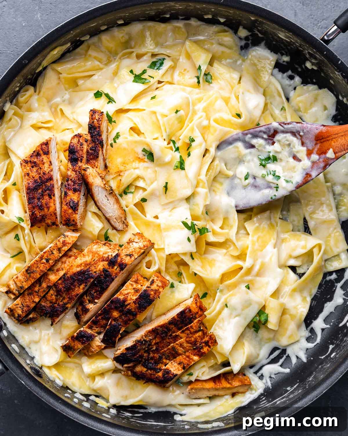 Creamy Chicken Alfredo Pasta Recipe 2 Overhead shot of alfredo pasta with pieces of blackened chicken on top.