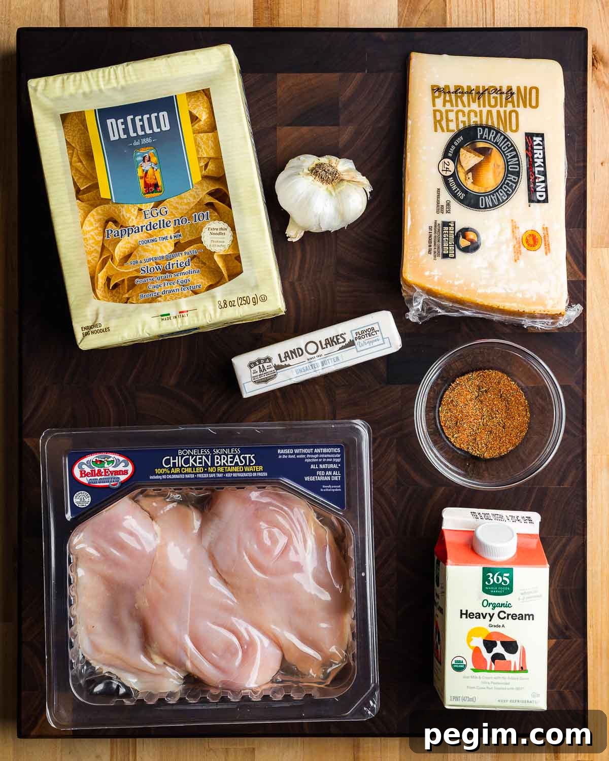 Creamy Chicken Alfredo Pasta Recipe 3 Ingredients shown: egg pappardelle, garlic, Parmigiano Reggiano, butter, blackened spice, chicken breasts, and heavy cream.